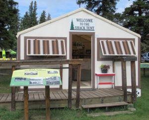 Welcome to the Shack Tent sign on wooden, tent-like building with interpretive signage in front