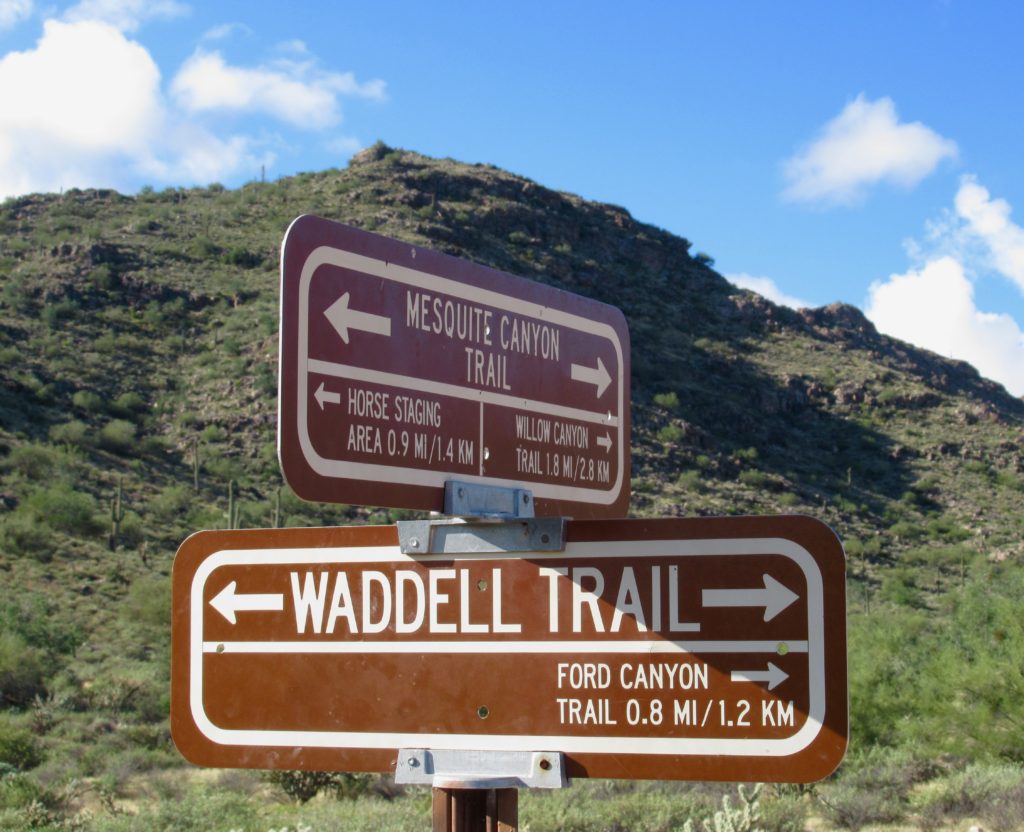 Trail signs point the way to Mesquite Canyon Trail and Waddell Trail.