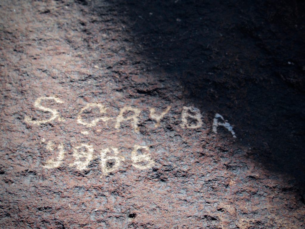 Name S. Gryba and date 1966 carved into brown rock