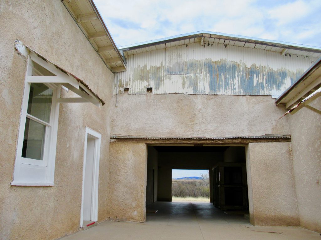 Dark breezeway joins multiple sections of adobe ranch house.