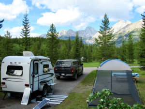 Truck and trailer set up in treed campsite with distant mountains