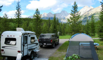 Truck and trailer set up in treed campsite with distant mountains