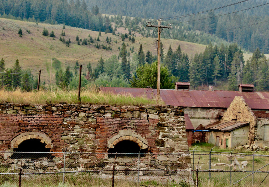 Old brick ovens and building with rusty metal roof.