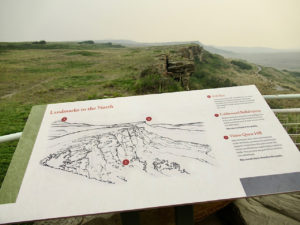 White interpretive sign on cliff edge point out landmarks in the north.