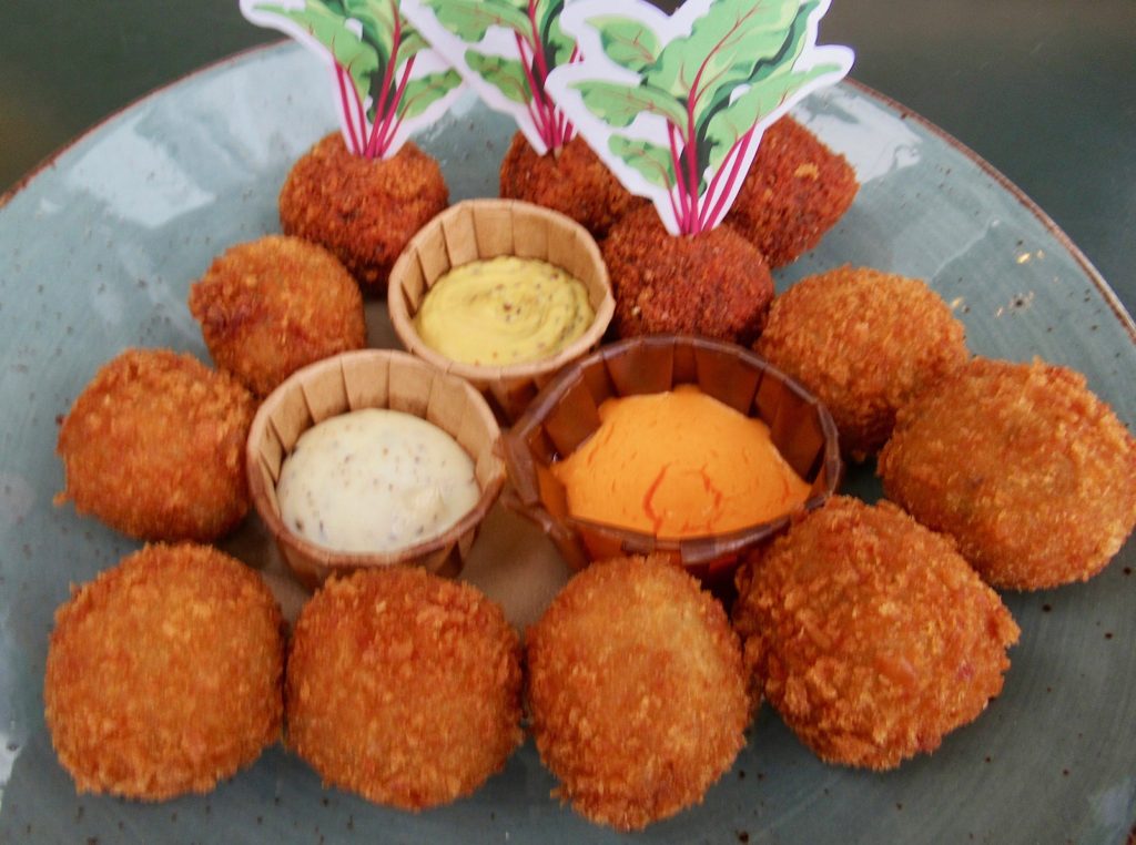 Crunchy fried snack balls on a plate with three dips.