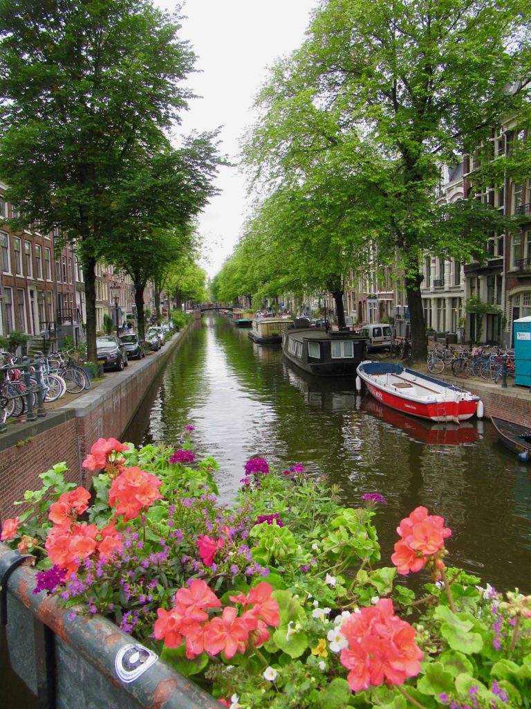 Photo of flower box on a bridge above a tree-lined canal with boats.