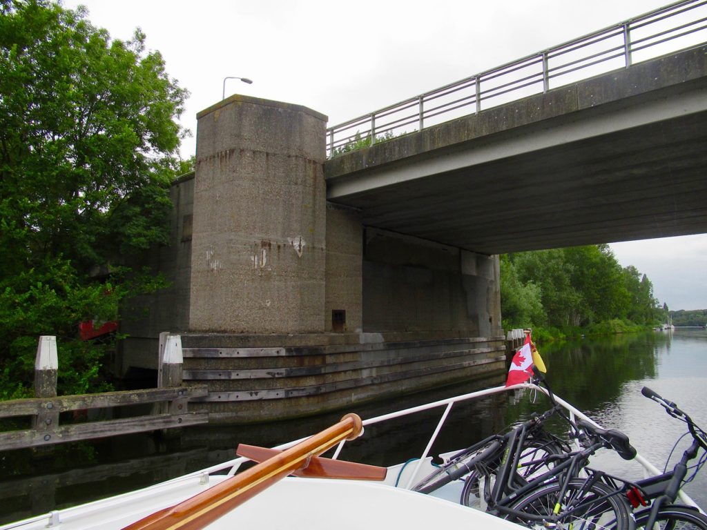 Front of a cruiser on a narrow canal going under a bridge.