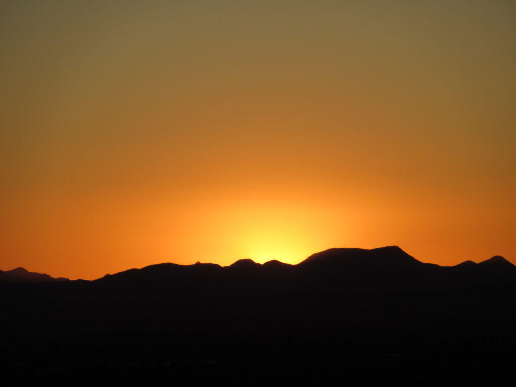 Silhouette mountains in front of glowing orange sky.