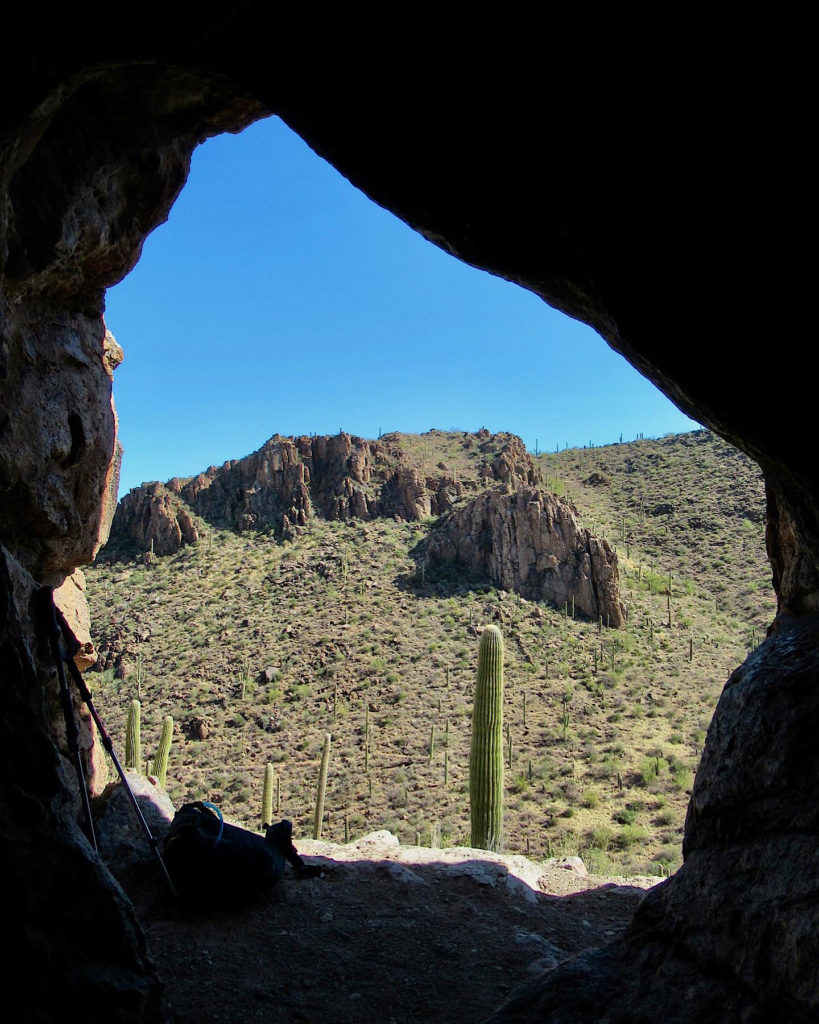 Silhouette of cave entrance framing desert mountain view.