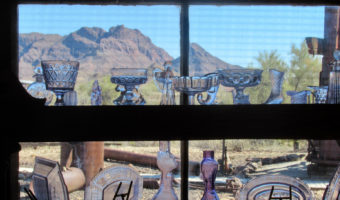 Historic pieces of glassware perched on window frame with mountains in distance.