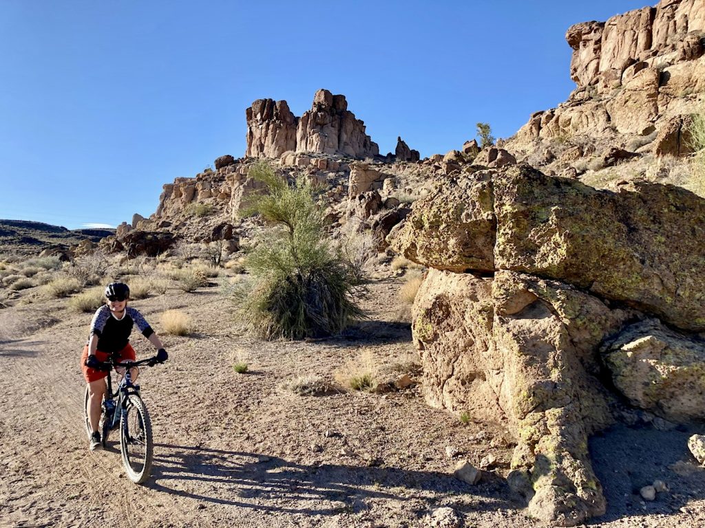 Woman on mountain bike in front of rugged rocky hills.