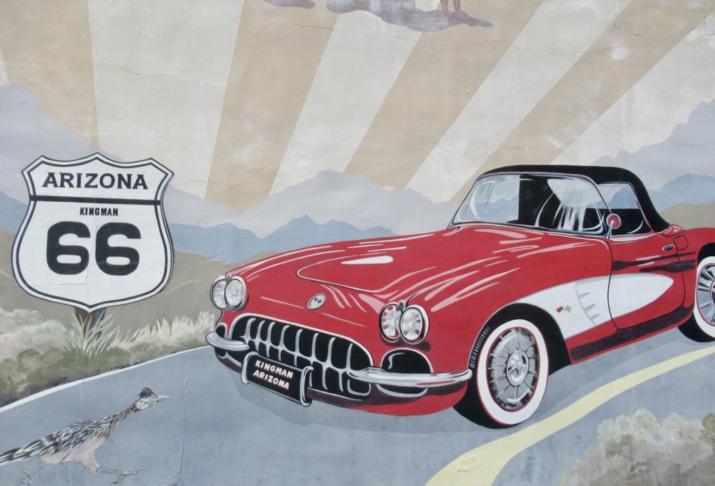 Painting of red and white vintage Corvette and roadrunner on paved road with Route 66 sign in front of car.
