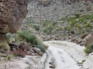 Deeply rutted white rock in brown rocky canyon.