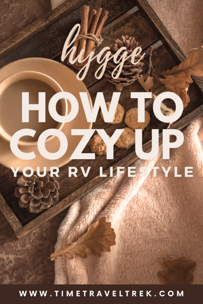 Pin image for Time.Travel.Trek. blogpost Hygge How to Cozy up Your RV Lifestyle text over warm brown toned image of a coffee mug, a blanket and pinecones. 