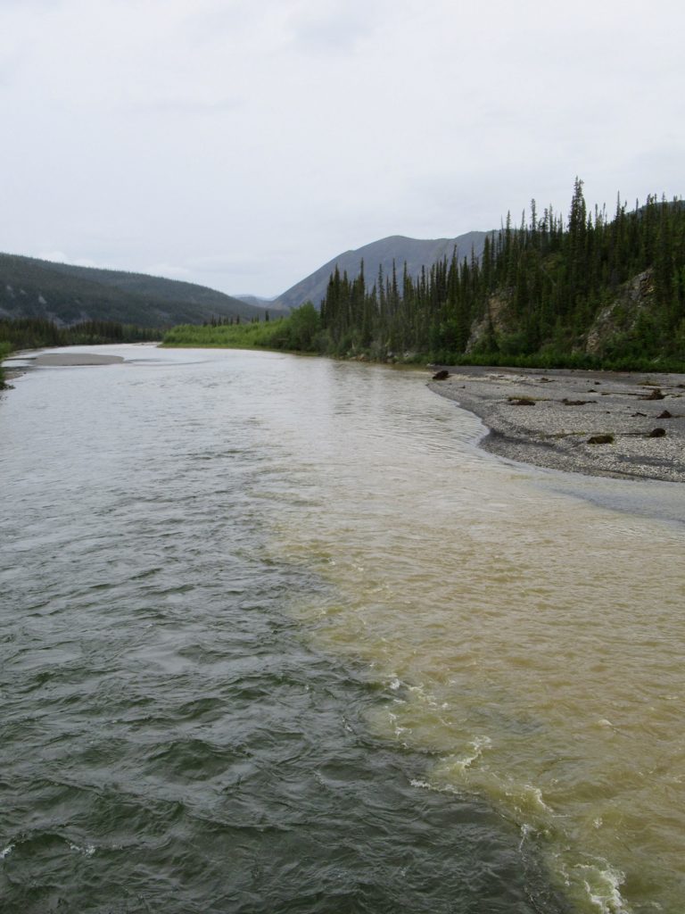 Dark greenish-blue river on left side with reddish brown water on right side.