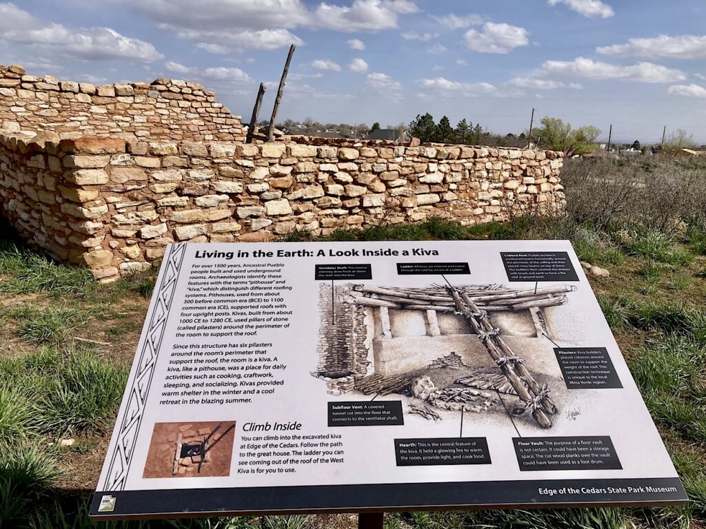 Interpretive sign discussing kivas and their structure in front of  reconstructed kiva.
