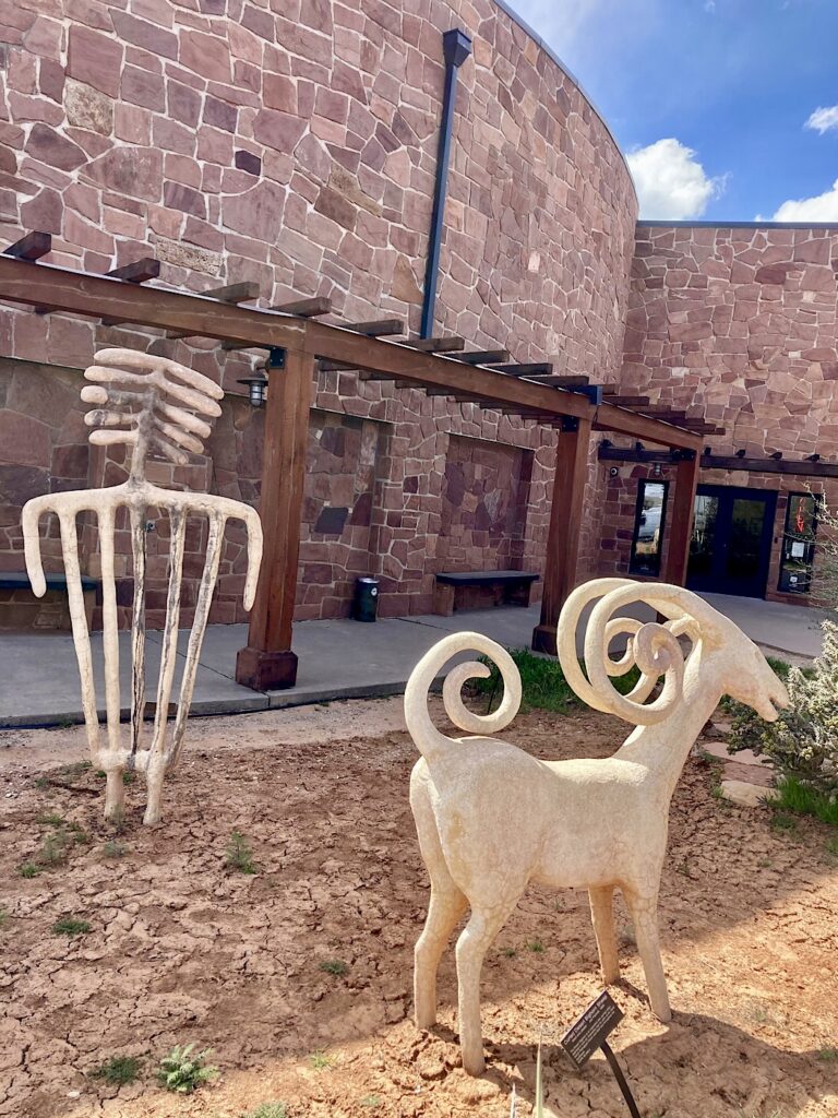 Three-dimensional sculptures of prehistoric rock art figures including a sheep and an anthropomorphic figure.