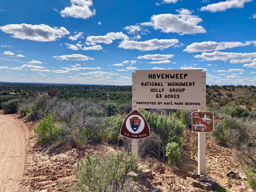 Wooden sign at edge of dirt road reading: Hovenweep National Monument. Holly Group. 63 Acres. Protected by National Park Service. U.S. Fee Area. No OHV's.