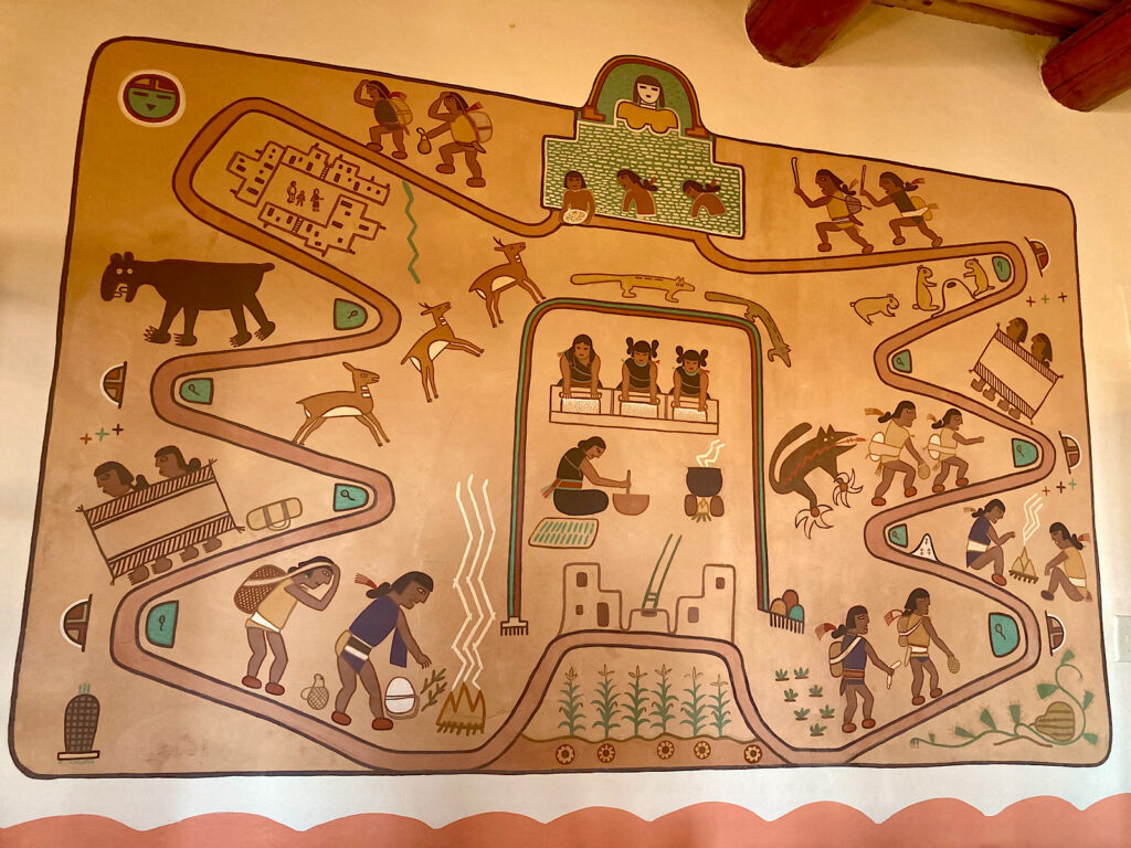 Painted mural with people, corn, and animal figures. 