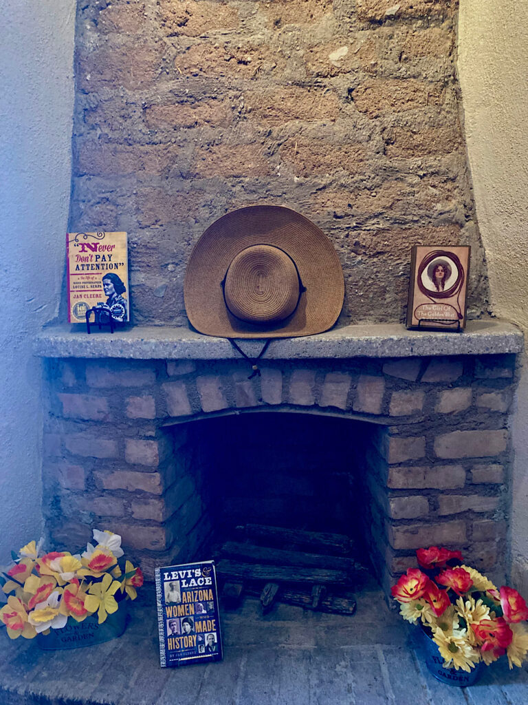 Historic brick fireplace with memorabilia and books on mantel.