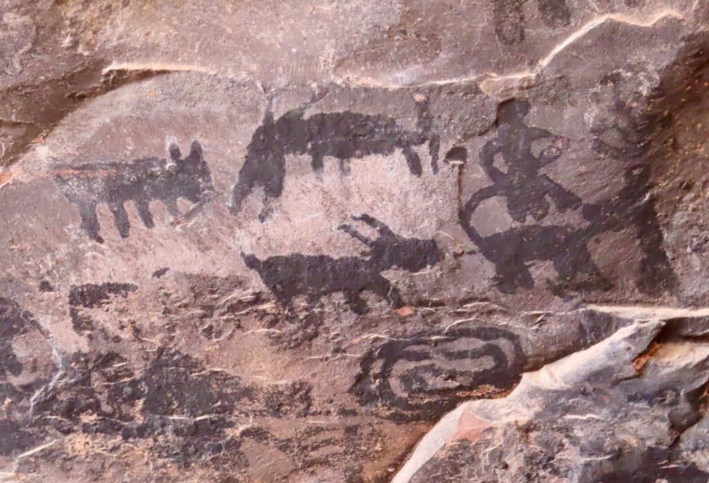Rock art images blackened by soot from fire.