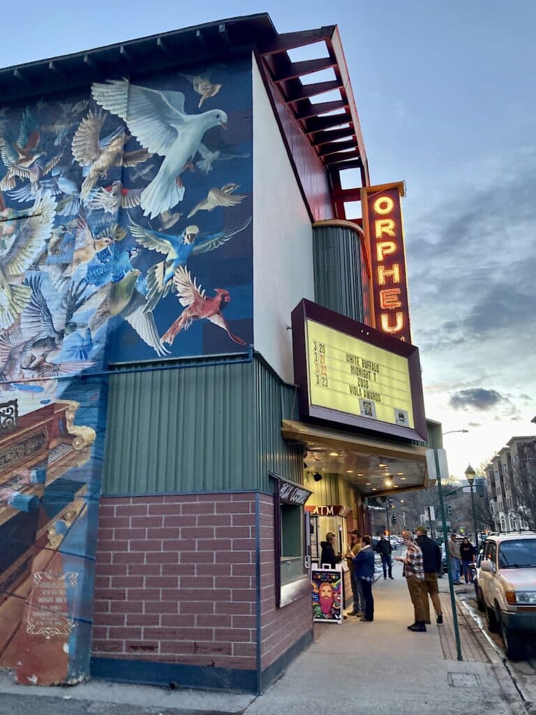 Theatre building and side wall mural of birds with marquee reading Orpheum and White Buffalo.