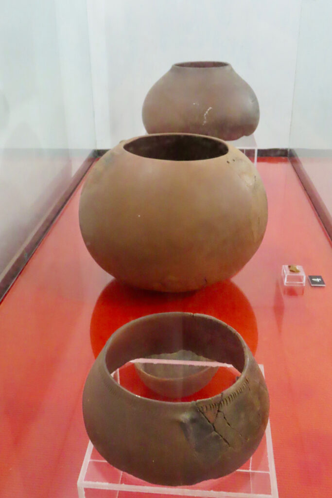 Three small clay pots in a glass case with red bottom.