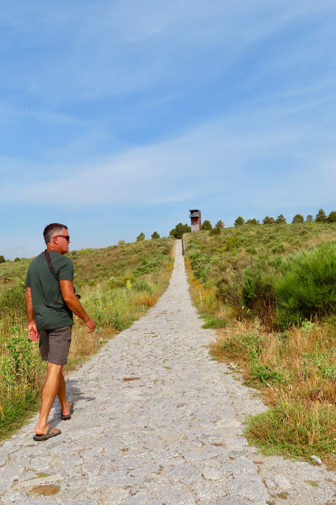 Man walking on cobblestone path leading up a slight hill to a building.