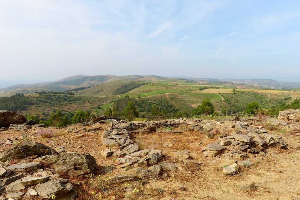 Stone outline of building ruins with scenic rolling green hillside beyond.