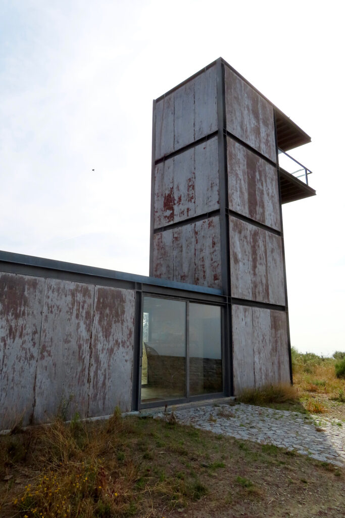 Metal clad building with tall tower attached.