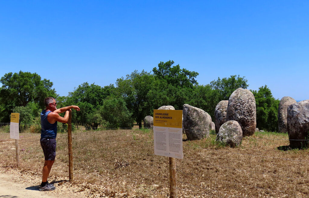 Man leaning on fence looking at circle of stones.