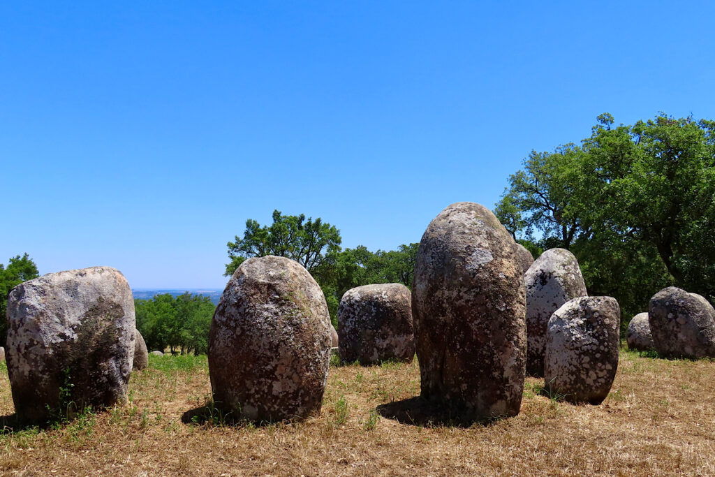 Circle of large standing stones under blue sky.