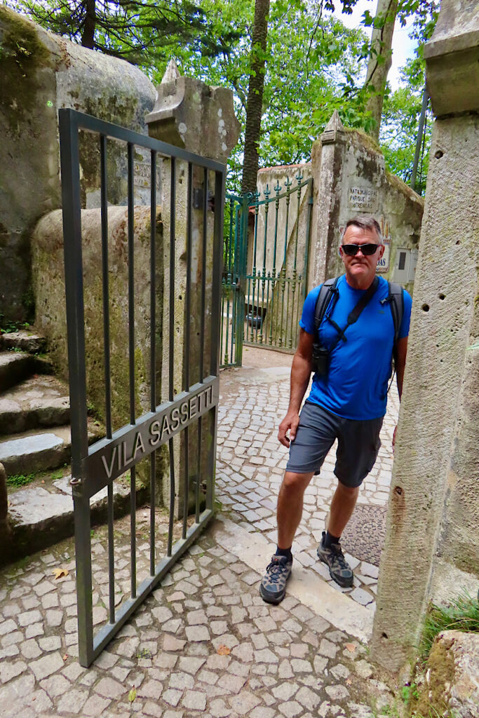 Man in blue shirt and shorts stepping through black metal gate.