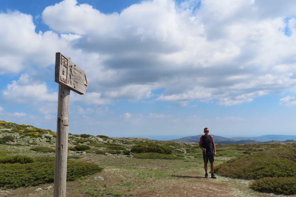 Hiker in distance beyond wooden trail sign.