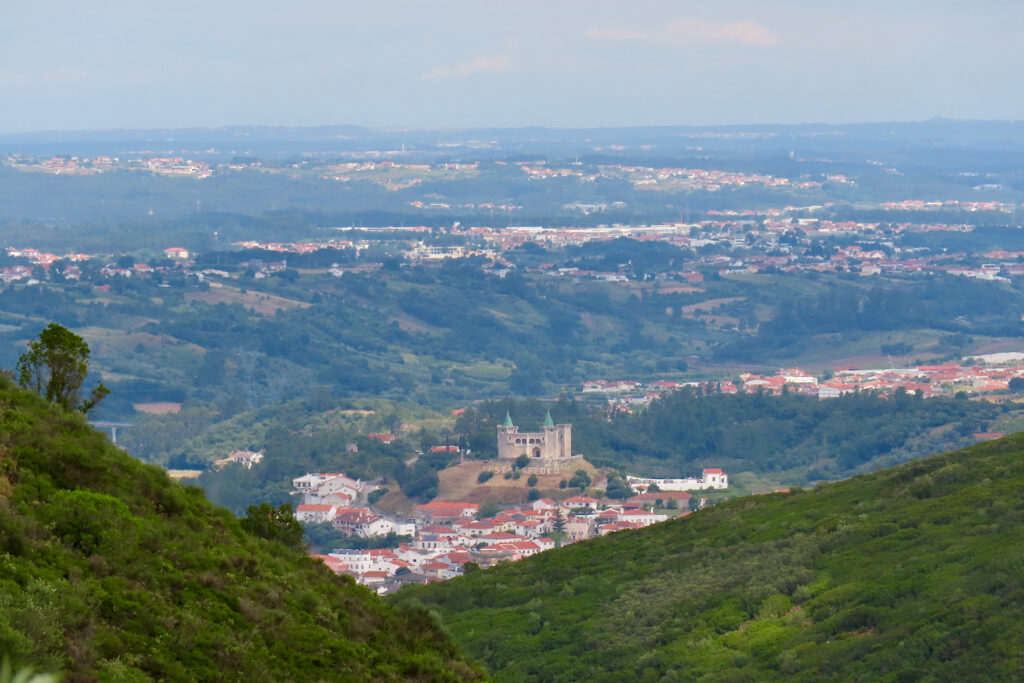 Green hillside with distant town made up of white buildings with red roofs.