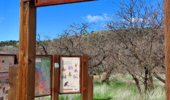 Metal sign raised on tall poles under blue sky. Sign reads: Welcome to V Bar V Ranch.