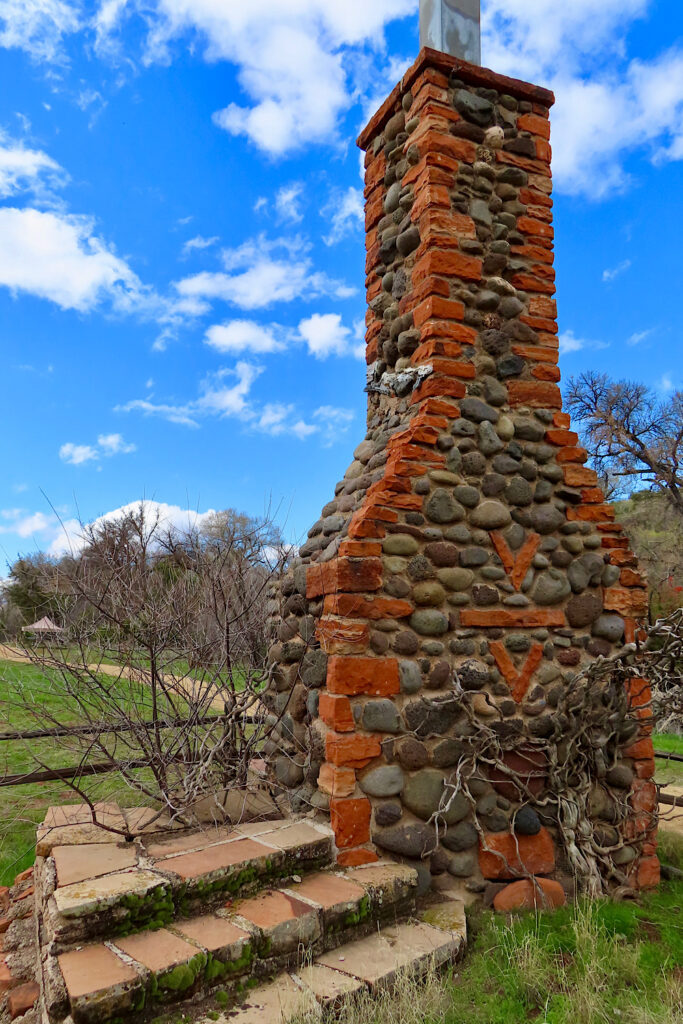 Old concrete steps and rock chimney under blue sky.