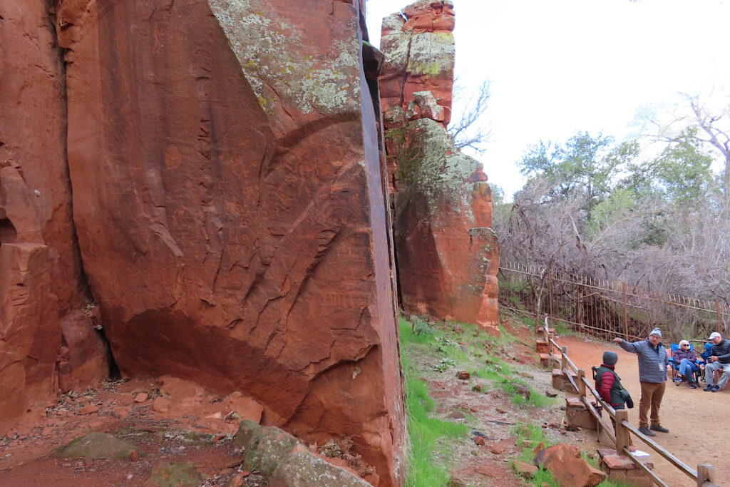 Large red sandstone wall with people standing below.