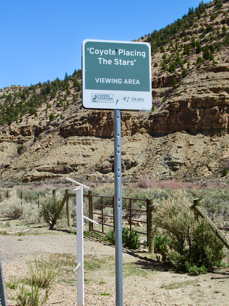 Green and white sign reading "Coyote Placing Stars Viewing Area" in front of white pole with three white tubes mounted at different heights and pointing different directions.