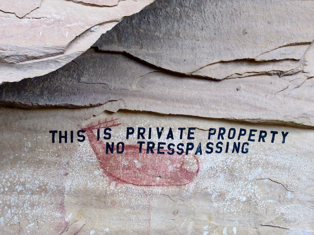 "No Tresspassing" written in black ink over red painting of a deer.