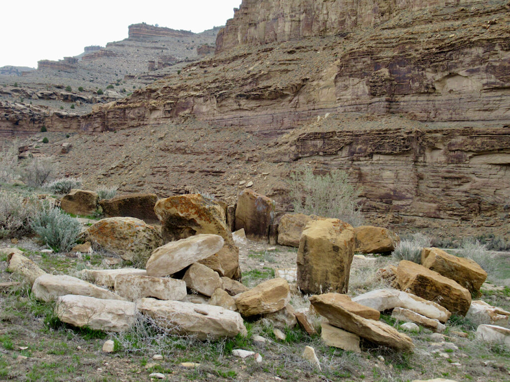 Rocks in semi-circle below tall cliff.