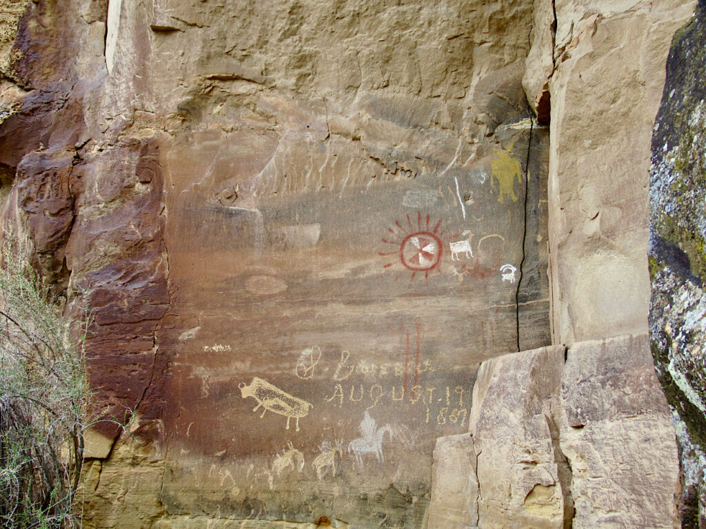 Red shield painted on rock with pecked rock art images below.