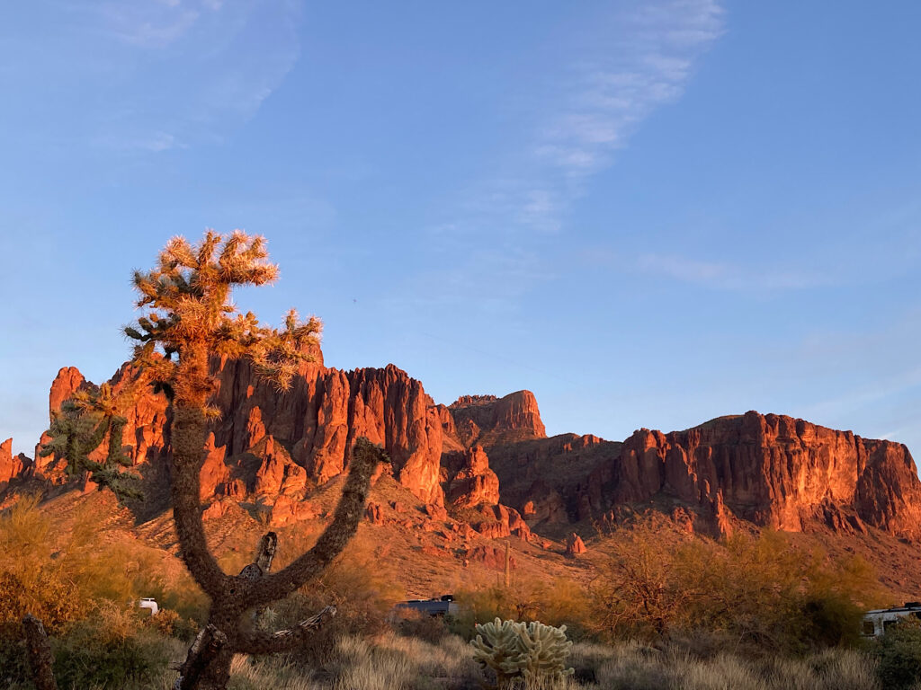 Rosy red light on mountain peak under blue sky.