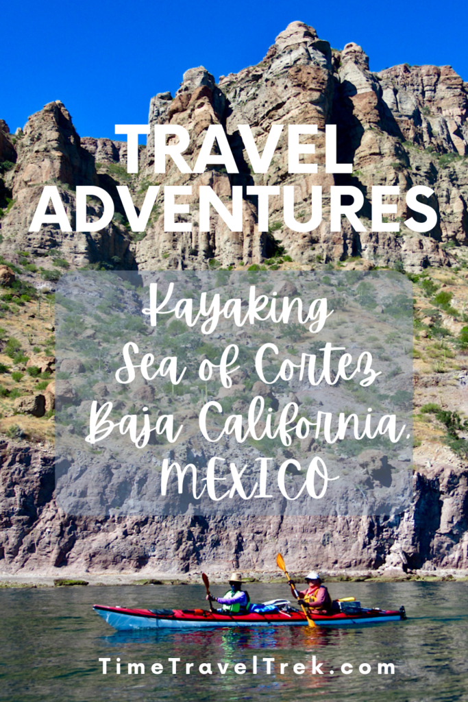 Pin image for TimeTravelTrek post reading "Travel Adventures: Kayaking Sea of Cortez Baja California Mexico" over image of two people in tandem kayak below steep cliffs.