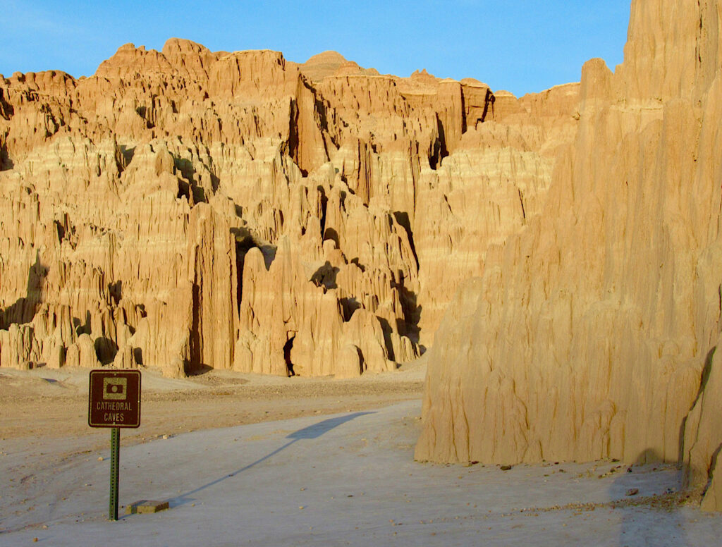 Evening sun glowing on eroding cliffs under blue sky.