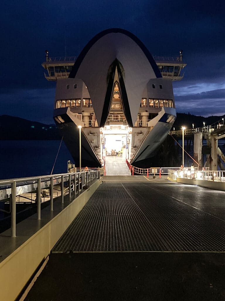 Nightfall with large ferry waiting for vehicle to board.