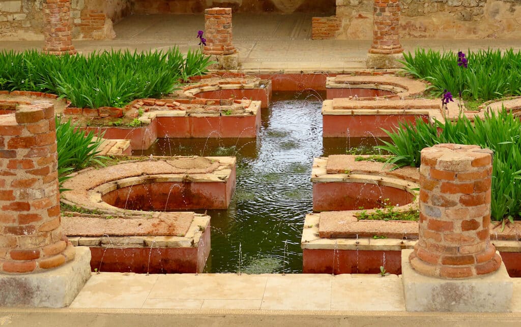 Horshoe-shaped brick fountains with irises planted in between.