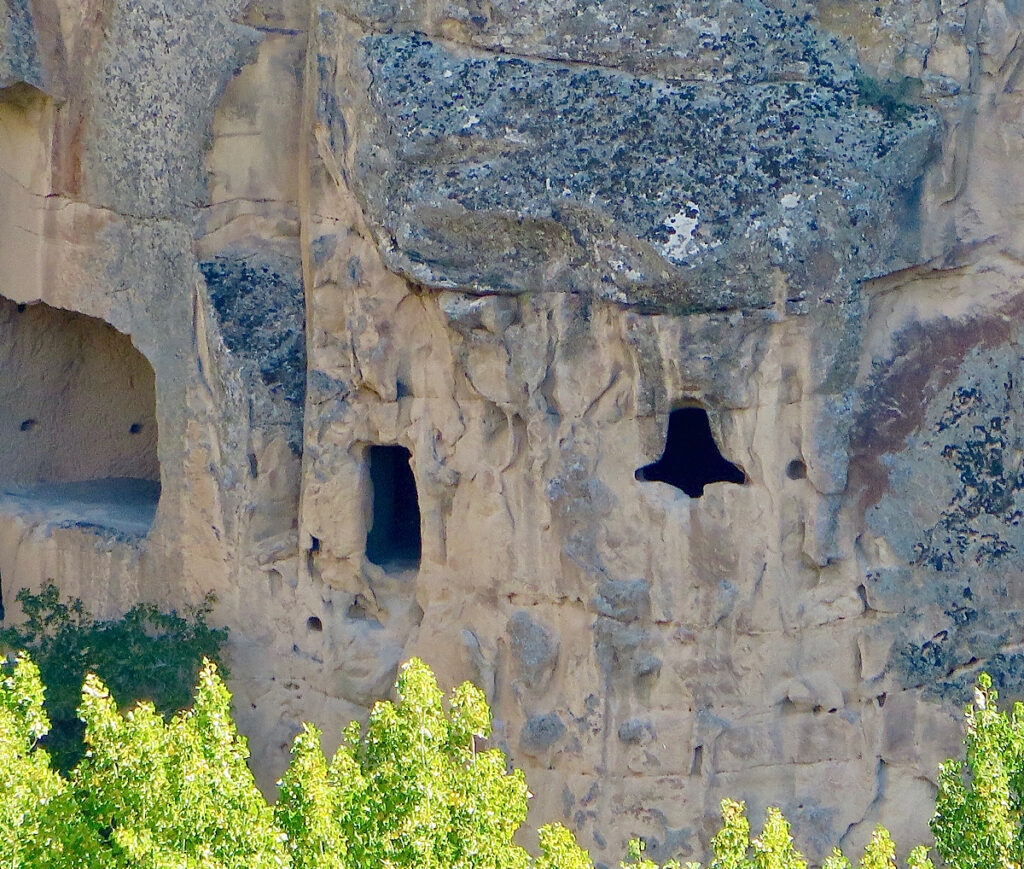 Rock wall with carved recesses including one in the shape of a bell.