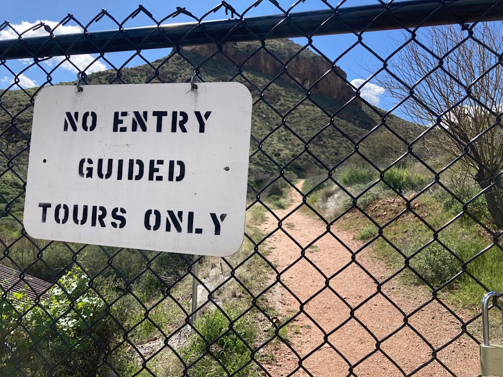 Chain link fence with white sign. Sign reads: No Entry. Guided Tours Only.