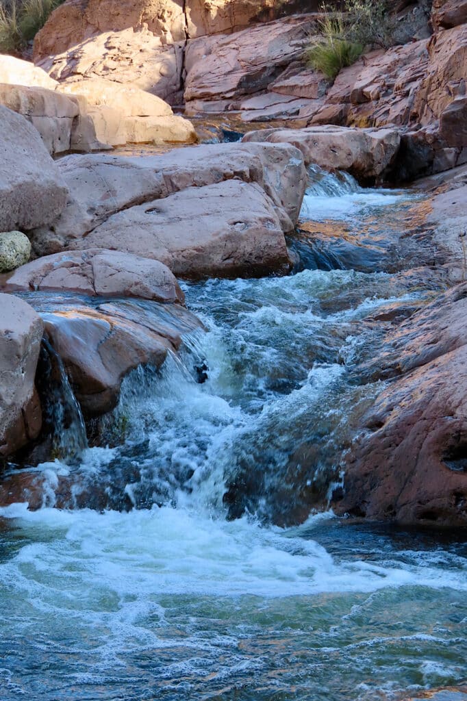 Small tumbling waterfall over pink pillowy sandstone rock.